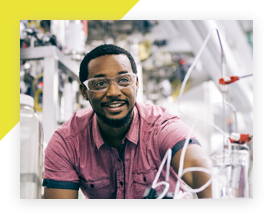 Worker wearing safety glasses, in a laboratory and smiling 