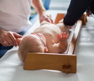 Infant being measured for length with an infantometer by two health care providers